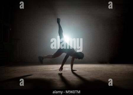 young male placing one hand firmly on the ground outdoors. break dance movement. controling movements Stock Photo