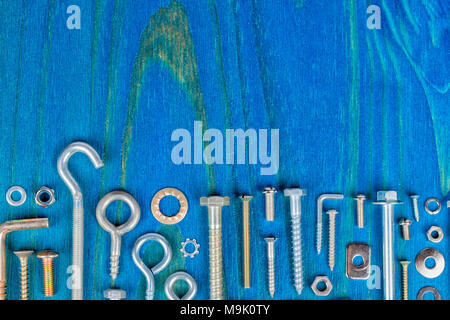 A lot of bolts nuts and washers of different types and sizes on a wooden background painted blue. Stock Photo