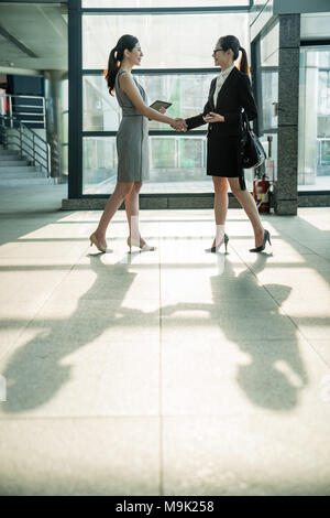 Two Asian business lady finish their successful negotiation and shake their hands to celebrate their partnership. Stock Photo