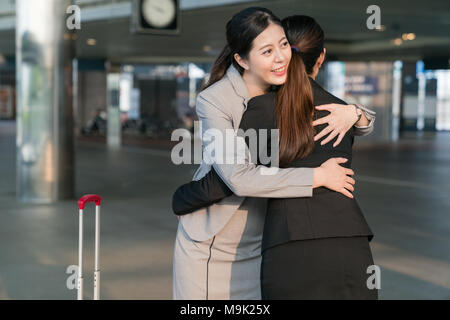 Two Asian business lady meet in the stration hugging each other happliy. Stock Photo