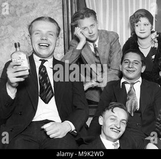 Young people drink bootleg whiskey labeled “Old Log Cabin” during Prohibition in Chicago in 1927.  “Old Log Cabin” was Canadian Club Whiskey imported by gangster Al Capone and Bugs Moran then rebottled and distributed in the Chicago area. Stock Photo