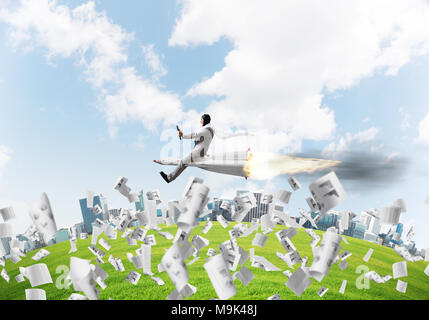 Conceptual image of young businessman in suit flying on rocket among flying papers with cityscape and blue sky on background. Stock Photo