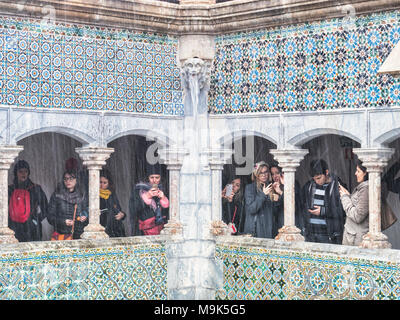 5 March 2018: Sintra, Portugal - Tourists with camera phones under a colonnade at Pena Palace, making the most of a very wet day. Stock Photo
