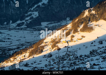 A strip of sunlight shining on the slopes and houses of the village of Amden above the Walensee, Glarus, Switzerland Stock Photo