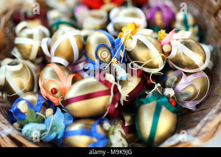 Shiny golden eggs in wicker basket. Decorated eggs with satin ribbon. Stock Photo