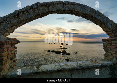 Silhouette of rocks in the sea, Framed by a Old arch at sunrise Stock Photo