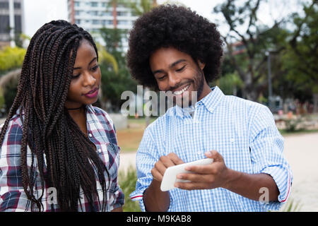 African american hipster man showing pictures at phone outdoors in the city Stock Photo