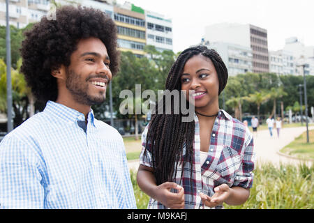 African american woman with dreadlocks flirting with hipster man outdoors in the city Stock Photo