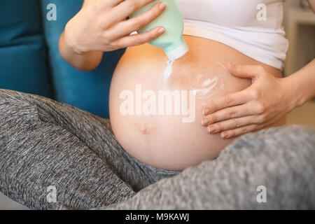 closeup pregnant woman applying moisturizing cream at her belly for prevention of stretch marks. Pregnancy, products for pregnant, healthcare, prevent Stock Photo
