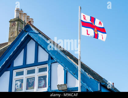 North Berwick, East Lothian, Scotland, UK. RNLI flag, with anchor symbol, on flagpole above half timbered old lifeboat station fluttering in wind Stock Photo