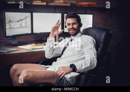Funny trader in headset underpants looking at camera working at home on computer, happy investor excited by market jump, successful deal online, stock Stock Photo