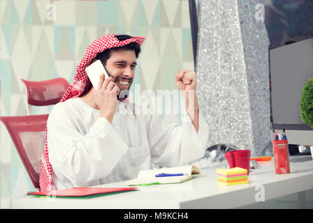 young Arabian business man talking on mobile phone and working finance about cost with laptop computer. Stock Photo