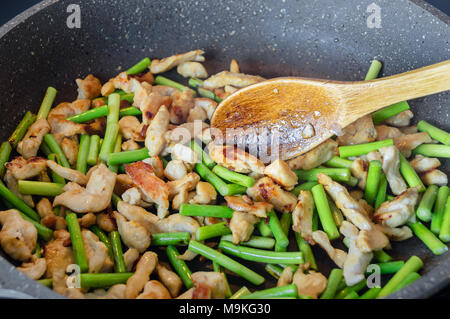 Arrows of garlic and pieces of meat are fried in a skillet according to the recipe for cooking Asian home-made noodles Stock Photo