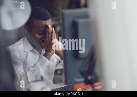 Stressed tired freelancer is having headache and thinking how to finish his work. Stock Photo