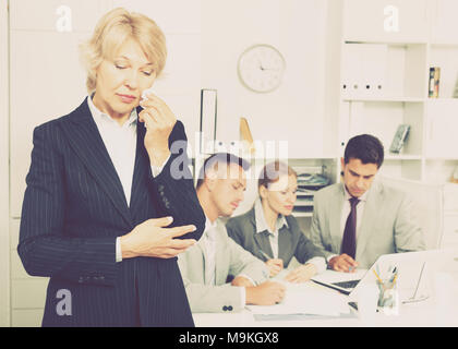 Business team tensely solving problems in office with upset woman foreground Stock Photo