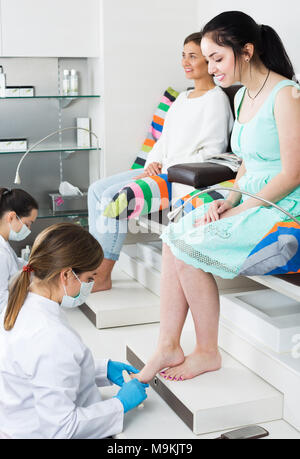 Female friends enjoying and relaxing at beauty spa while getting pedicure Stock Photo