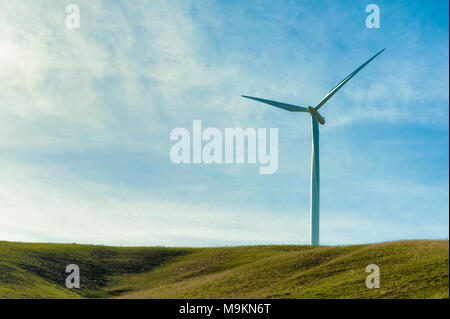 Wind Turbines stand tall and stark against the high desert landscape of rolling hills in the Columbia River Gorge Stock Photo