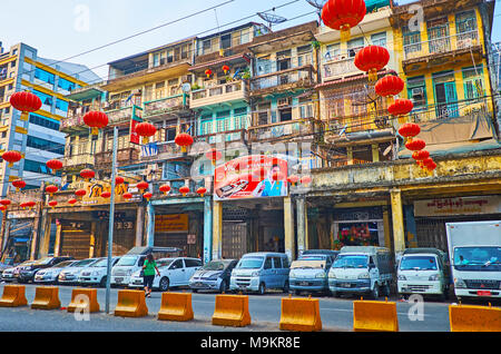 YANGON, MYANMAR - FEBRUARY 14, 2018: The old shabby residential building at Maha Bandula Road with decorative Spring Festival lanterns on the foregrou Stock Photo