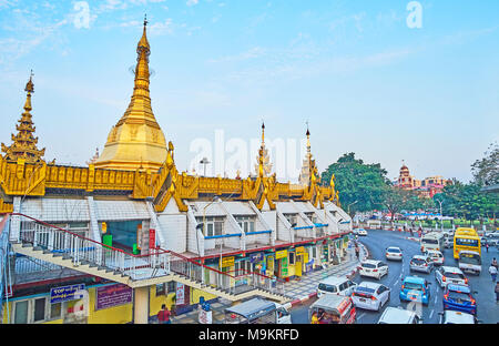 YANGON, MYANMAR - FEBRUARY 14, 2018: The heavy traffic on the roundabout road at Sule Pagoda with a view on lush greenery of Maha Bandula Park and tow Stock Photo