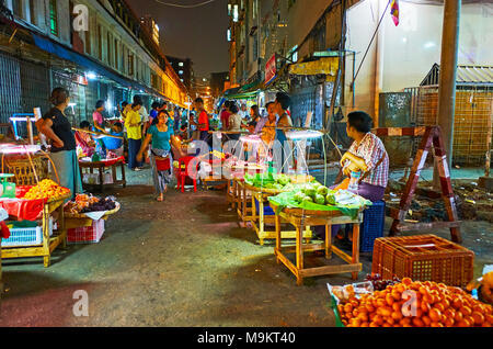 YANGON, MYANMAR - FEBRUARY 14, 2018: The narrow street in Chinatown is used by the numerous stalls of food market, full of fresh fruits and vegetables Stock Photo