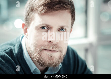 Calm handsome man sitting and looking straight. Stock Photo