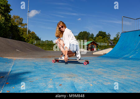 a teenage girl with a skateboard on halfpipe in the park Stock Photo