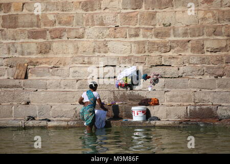 Indian woman washing clothes and dishes on the river - inderin beim waschen von Kleidung und geschirr am fluss Stock Photo