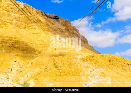 MASADA, ISRAEL - MARCH 16, 2018: The cliff and fortress of Masada, cable cars and visitors climbing the snake path, on the eastern edge of the Judaean Stock Photo