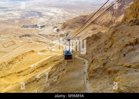 MASADA, ISRAEL - MARCH 16, 2018: The cliff and fortress of Masada, cable cars and visitors climbing the snake path, on the eastern edge of the Judaean Stock Photo