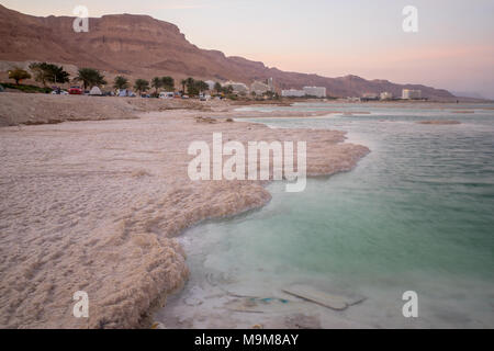 EIN BOKEK, ISRAEL - MARCH 16, 2018: Sunset view of salt formations in the Dead Sea, Ein Bokek resort, and visitors. Southern Israel Stock Photo