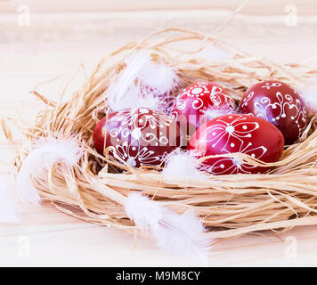 Easter eggs festive painted, decorative eggs on a straw nest with feathers Stock Photo