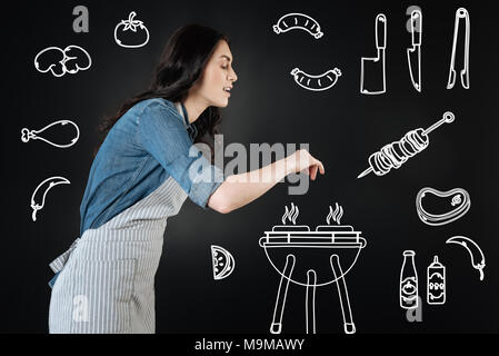 Smiling young woman adding spices while making barbeque Stock Photo