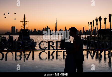 Silhouette of a romantic couple hugging at sunset in Dubai Stock Photo