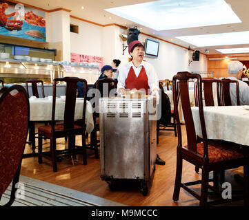 A chinese lady serving food from her dim sum trolley in the famous Restaurant Ruby Rouge in Montreal's chinatown Stock Photo