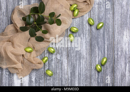 Easter chocolate eggs in foil with beige fabric on gray wooden background Stock Photo