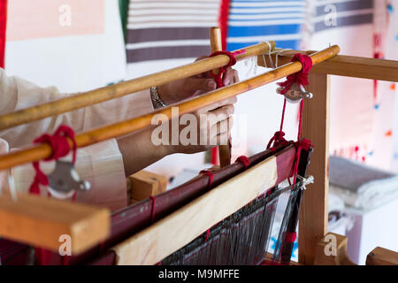 Hand of a weaver working on a loom manufacturing clothes in traditional old fashioned way Stock Photo