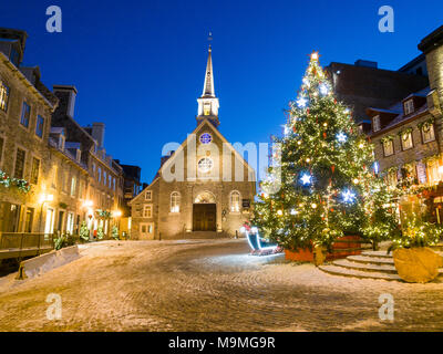 Notre Dame des Victorires and Christmas Tree: The small church in the touristic section of Lower Quebec with a large lit christmas tree in the empty square. Stock Photo