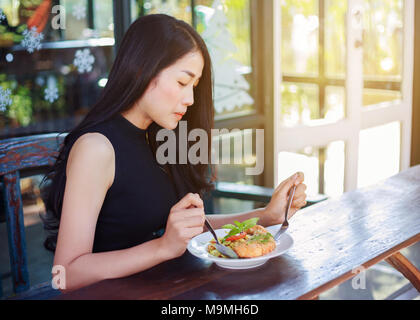 young woman eating food in a restaurant Stock Photo