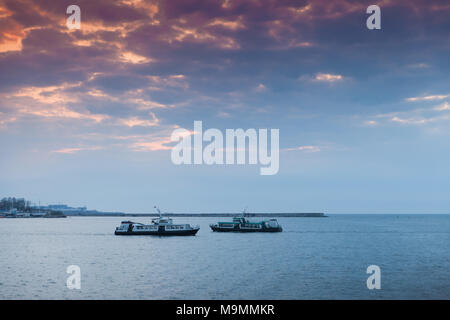 Two small passenger ships go under colorful evening sky. Landscape of Sevastopol Bay in sunset Stock Photo