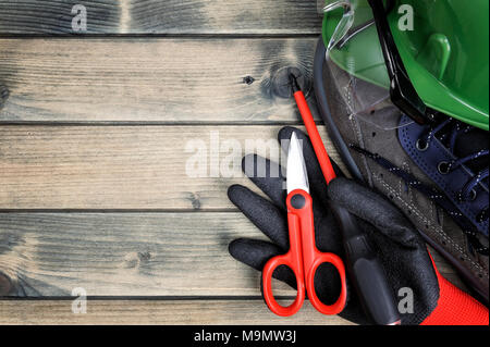 Close up of tools and workwear for electrical installation on an antique wooden table. Stock Photo