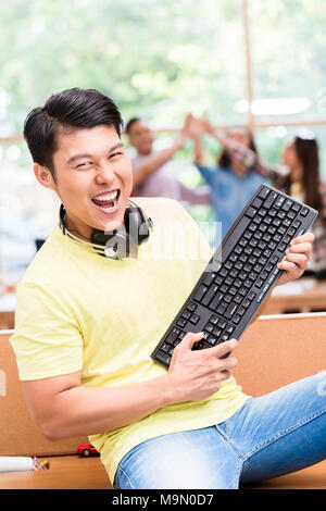 Young Chinese employee happy for his successful work on computer Stock Photo