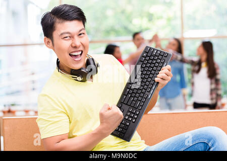 Young Chinese employee happy for his successful work on computer Stock Photo