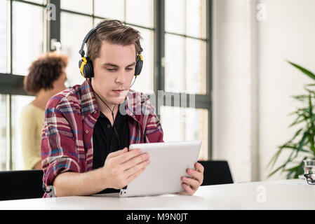 Young man watching a video on tablet PC at work Stock Photo