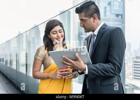 Two Indian colleagues using a tablet on the top of a building Stock Photo