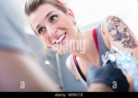 Cheerful woman smiling with confidence in a modern tattoo studio Stock Photo