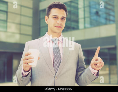 Businessman pressing imaginary button on large plant background Stock Photo