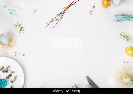 Easter table setting with gold and blue eggs and cutlery on white. Holidays background. Backdrop with copy space, flat lay, top view. Stock Photo