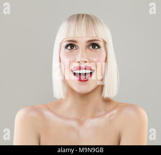 Beautiful blonde woman with bob hairstyle surprised and shocked looks up. Expressive facial expressions Stock Photo