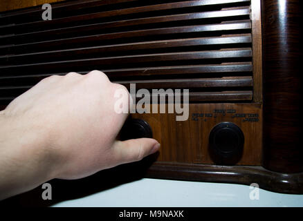 Hand turning knob on old radio Stock Photo