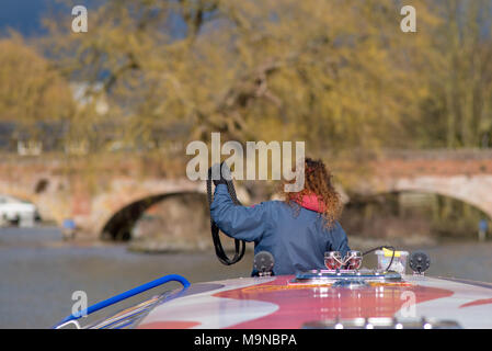 girl with red curly hair stood on front of canal boat with typical english buildings in background and fantastic light about to throw a lariat lasso Stock Photo